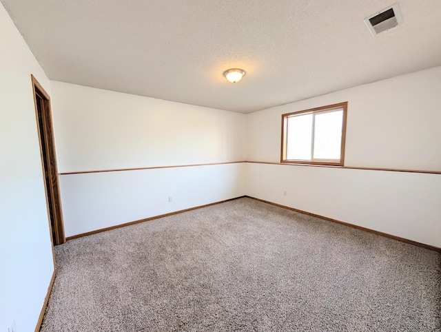 carpeted spare room featuring visible vents, baseboards, and a textured ceiling