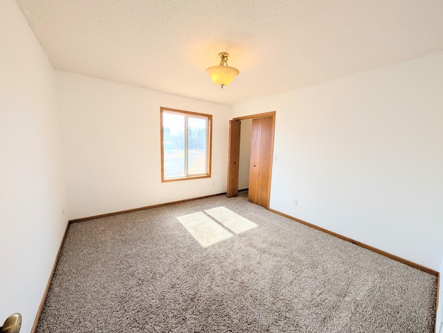 empty room featuring baseboards, carpet floors, and a textured ceiling