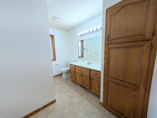 bathroom with vanity, baseboards, a textured ceiling, tile patterned floors, and toilet