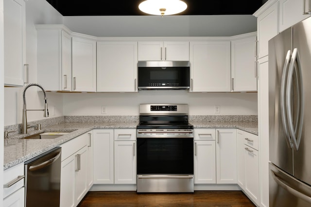 kitchen with sink, white cabinetry, appliances with stainless steel finishes, dark hardwood / wood-style floors, and light stone countertops