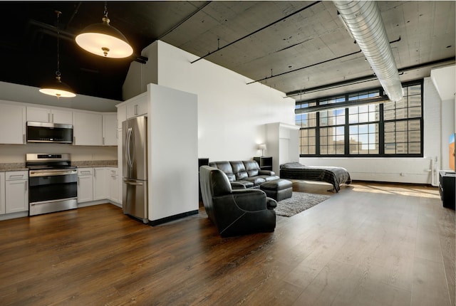 living room featuring a high ceiling and dark hardwood / wood-style flooring