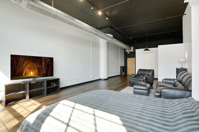 bedroom with hardwood / wood-style flooring, a towering ceiling, and track lighting