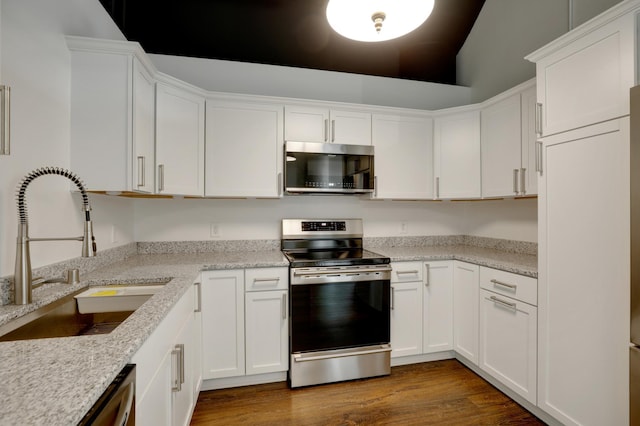 kitchen with dark wood-type flooring, sink, light stone counters, stainless steel appliances, and white cabinets