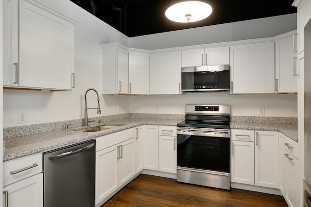 kitchen featuring appliances with stainless steel finishes, sink, white cabinets, light stone counters, and dark wood-type flooring