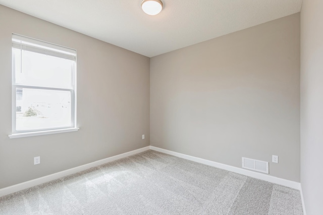 carpeted spare room featuring baseboards and visible vents