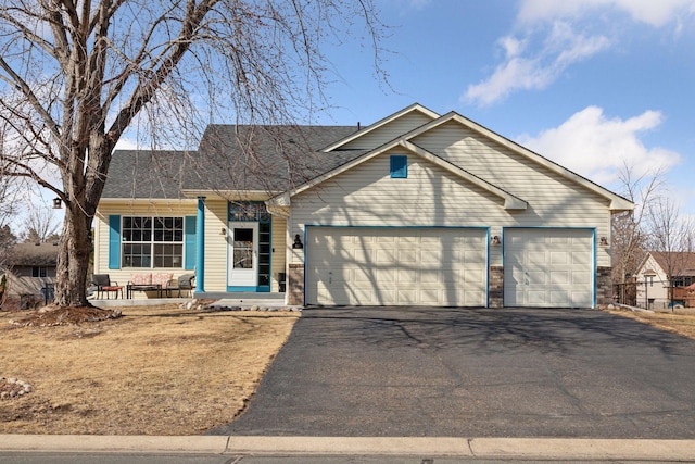 ranch-style home featuring aphalt driveway, an attached garage, and a shingled roof