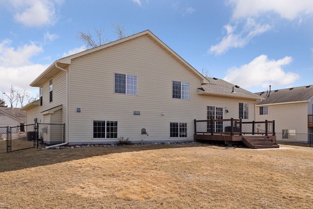 back of house with a deck, a gate, fence, and a lawn