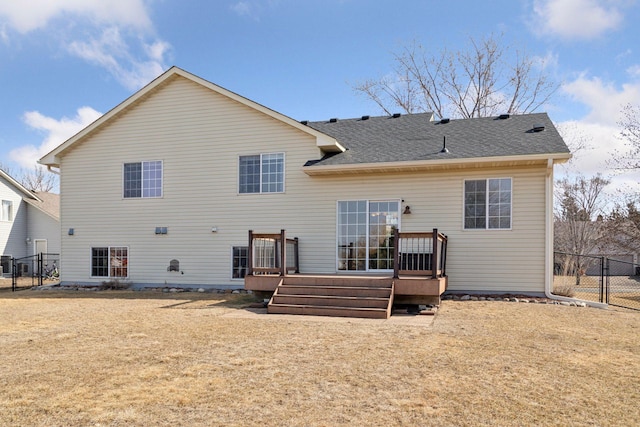 back of house featuring a lawn, a shingled roof, a deck, and fence