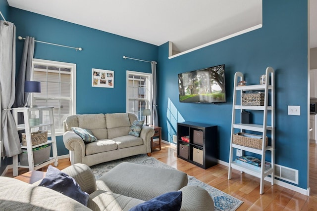 living area featuring wood finished floors, visible vents, and baseboards