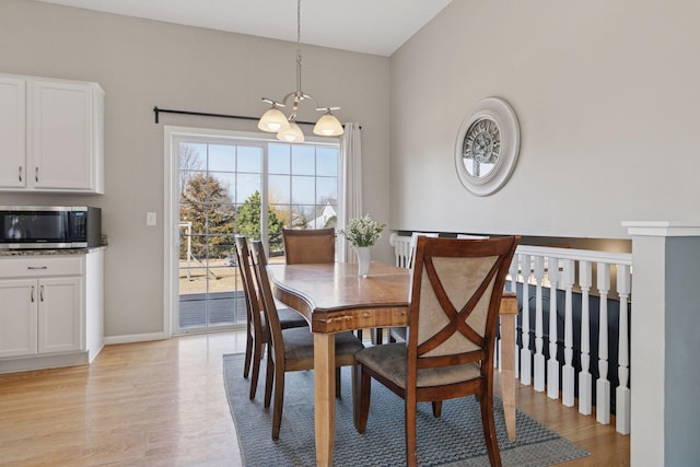 dining space featuring a notable chandelier, baseboards, and light wood finished floors