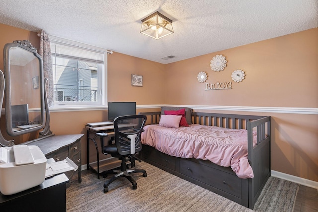 bedroom featuring visible vents, baseboards, a textured ceiling, and wood finished floors