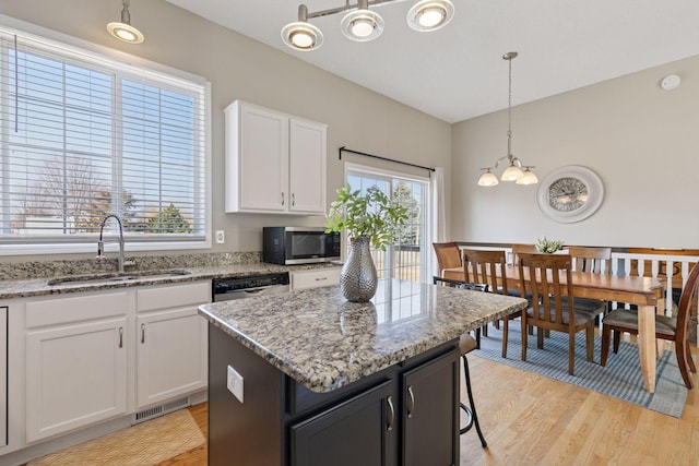 kitchen with visible vents, a sink, white cabinetry, stainless steel appliances, and light wood-style floors