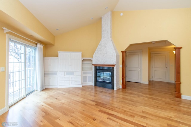 unfurnished living room with a fireplace, high vaulted ceiling, and light wood-type flooring