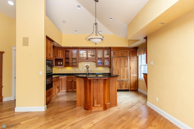 kitchen with pendant lighting, double oven, tasteful backsplash, a kitchen island, and light wood-type flooring