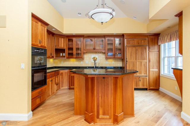 kitchen with tasteful backsplash, double oven, a kitchen island, and dark stone countertops