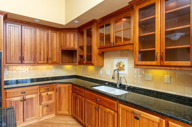 kitchen with tasteful backsplash, dark stone counters, and sink