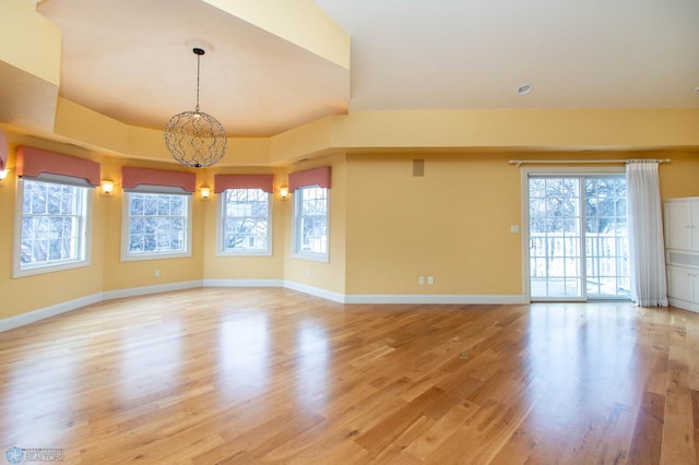 spare room with a tray ceiling and light wood-type flooring