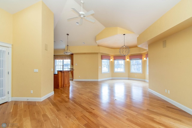 interior space featuring ceiling fan with notable chandelier, high vaulted ceiling, and light hardwood / wood-style flooring