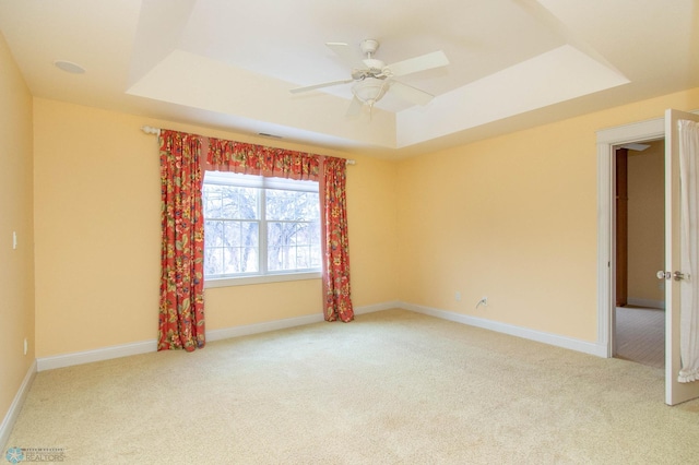 unfurnished room featuring light carpet, a raised ceiling, and ceiling fan