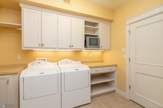 laundry room featuring light tile patterned flooring, cabinets, and washing machine and clothes dryer