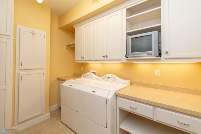 laundry area featuring cabinets, washing machine and dryer, and light tile patterned floors