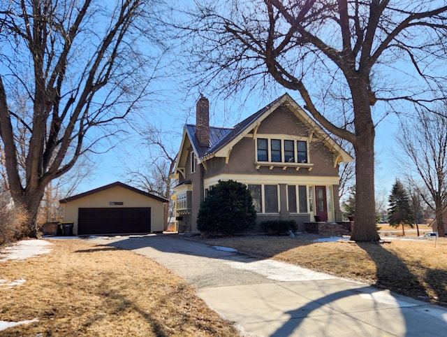 view of front of property with a garage, stucco siding, a chimney, and an outdoor structure