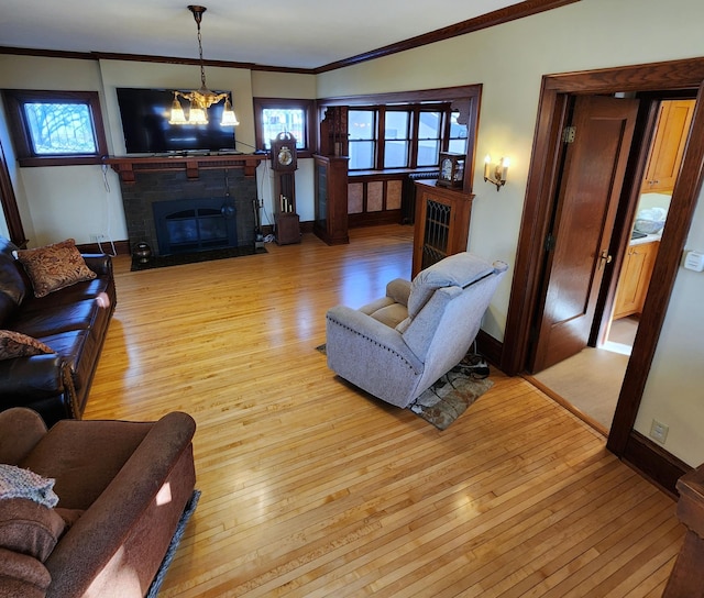 living area with crown molding, a fireplace, light wood-style floors, a chandelier, and baseboards