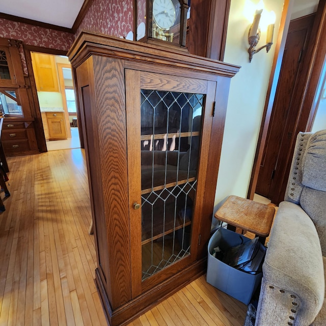 interior details featuring ornamental molding, wallpapered walls, and wood finished floors