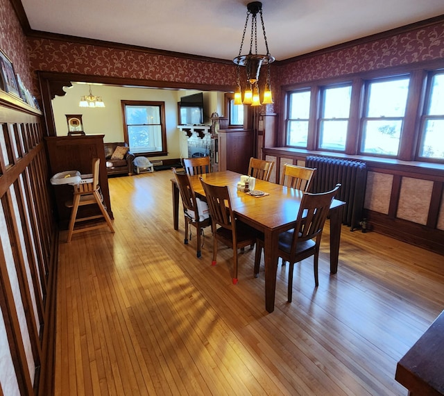 dining room featuring crown molding, radiator, an inviting chandelier, hardwood / wood-style floors, and wallpapered walls