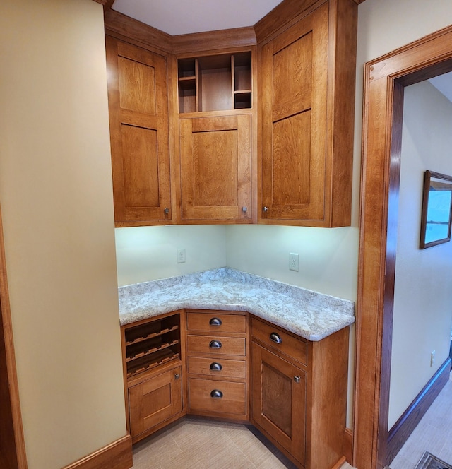 kitchen with open shelves, light stone countertops, and brown cabinets