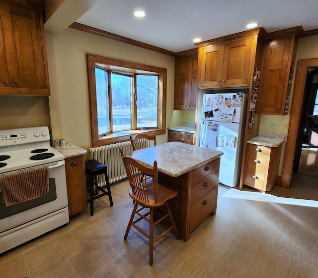 kitchen featuring a breakfast bar, radiator heating unit, brown cabinetry, light stone countertops, and white appliances