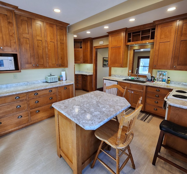 kitchen with white appliances, brown cabinets, a kitchen breakfast bar, light stone countertops, and a sink