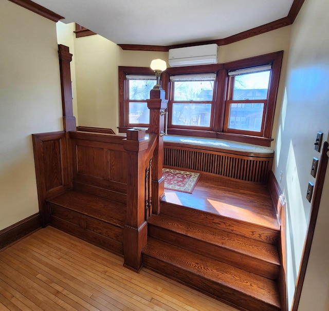 stairway featuring wood-type flooring, a wall unit AC, and baseboards