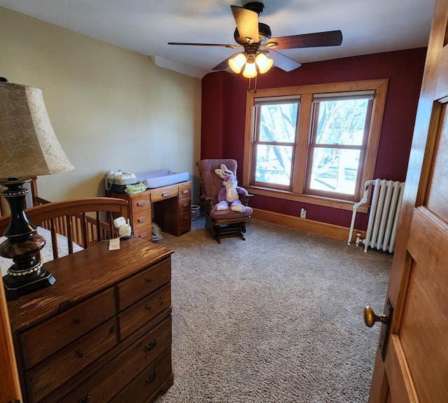 carpeted bedroom with radiator heating unit, baseboards, and a ceiling fan