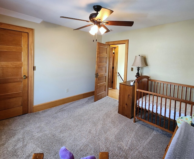 bedroom featuring carpet floors, a nursery area, ceiling fan, and baseboards