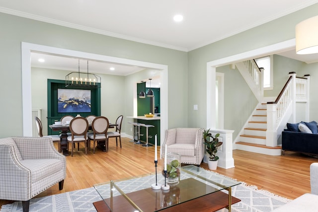 living room with wood-type flooring, ornamental molding, and a chandelier