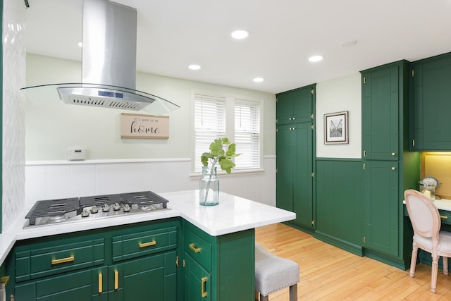 kitchen featuring island exhaust hood, stainless steel gas cooktop, light hardwood / wood-style flooring, and green cabinetry