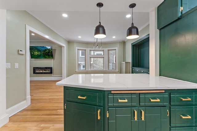 kitchen featuring crown molding, light stone countertops, green cabinets, and light hardwood / wood-style flooring