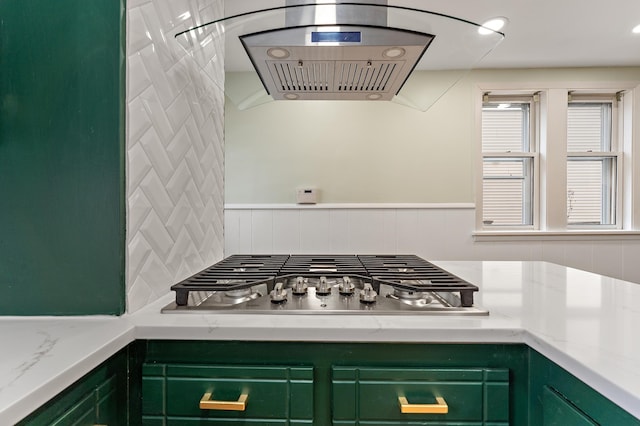 kitchen featuring tasteful backsplash, light stone countertops, stainless steel gas cooktop, and green cabinets