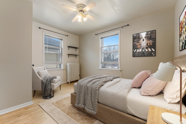 bedroom featuring radiator heating unit, ceiling fan, and light wood-type flooring