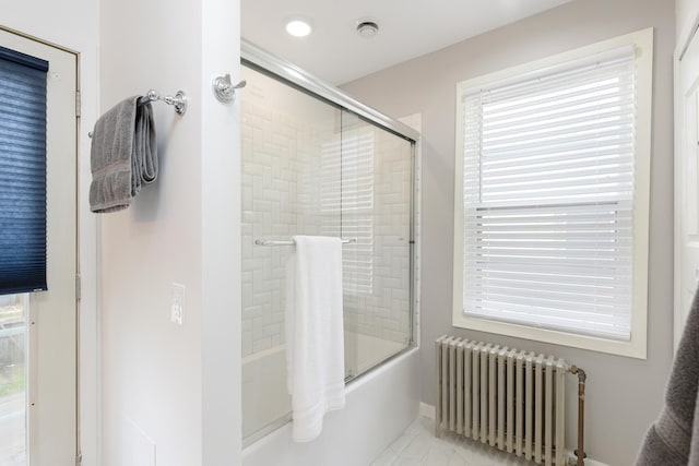 bathroom with tile patterned floors, radiator heating unit, bath / shower combo with glass door, and a wealth of natural light