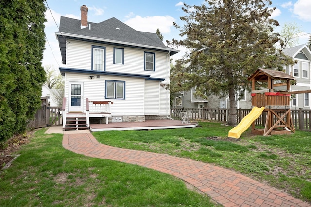 rear view of property featuring a wooden deck, a yard, and a playground