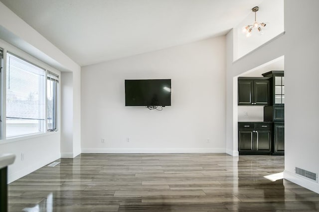 unfurnished living room with hardwood / wood-style flooring, vaulted ceiling, and a notable chandelier