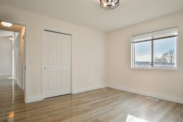 unfurnished bedroom with light wood-type flooring and a closet