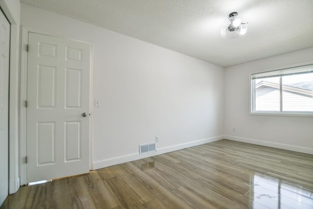 empty room featuring a textured ceiling and light hardwood / wood-style floors