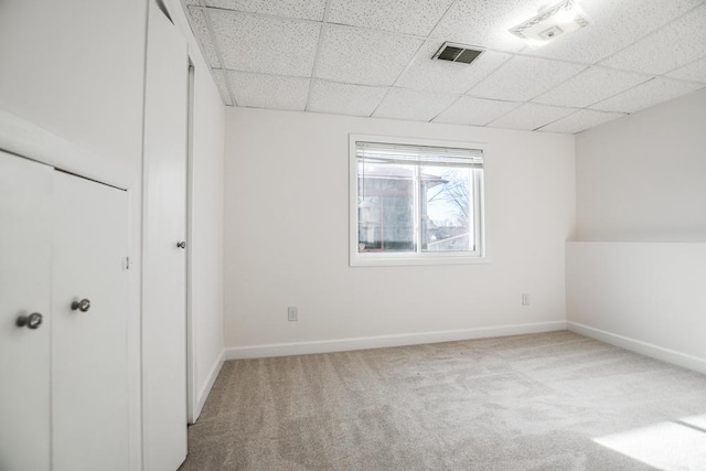 unfurnished bedroom with a paneled ceiling and light carpet