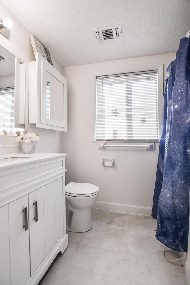 bathroom with vanity, tile patterned flooring, a textured ceiling, and toilet