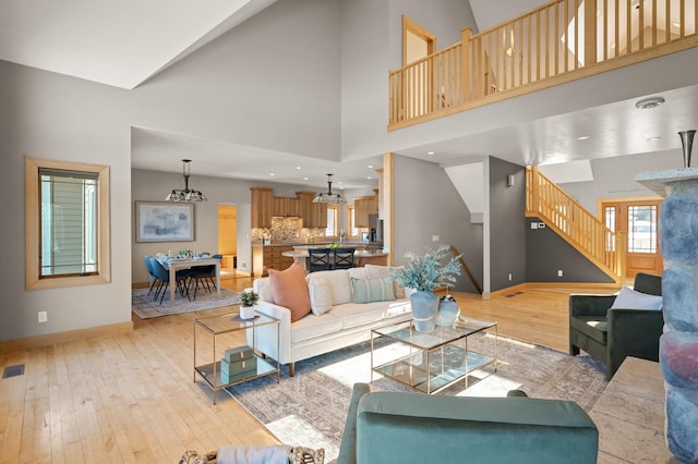 living room featuring high vaulted ceiling, an inviting chandelier, and light hardwood / wood-style flooring