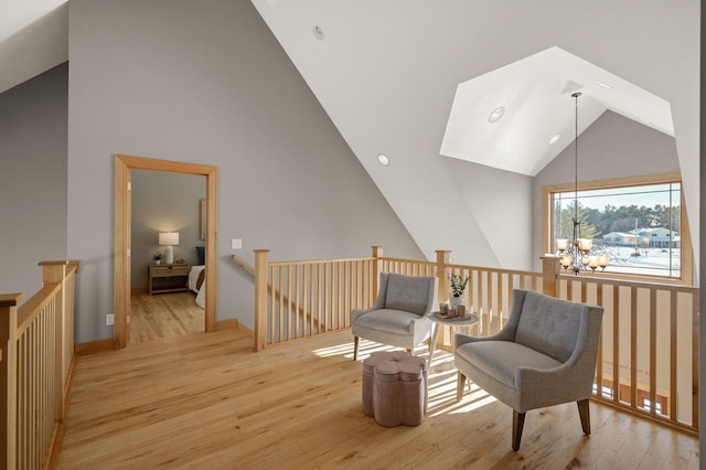 sitting room with light wood-type flooring, high vaulted ceiling, and an inviting chandelier