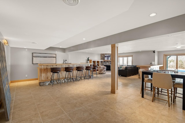 dining room featuring bar, plenty of natural light, decorative columns, and a fireplace